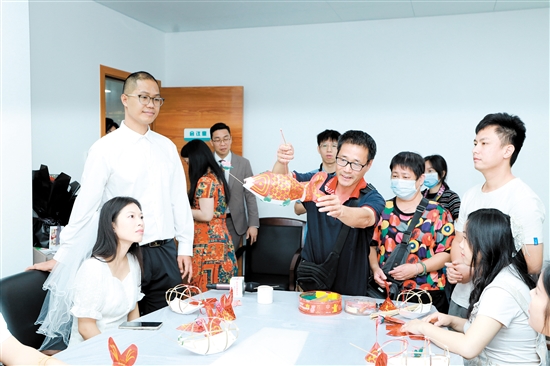 昨日，在新會(huì)區(qū)民政局婚姻登記處，工作人員向剛領(lǐng)證的新人們展示新會(huì)魚(yú)燈制作技巧。