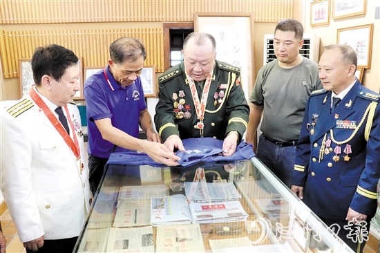 謝志高（中）現場展示他的“戰(zhàn)衣”，講述他保衛(wèi)邊疆那段艱苦難忘的戰(zhàn)爭歲月。