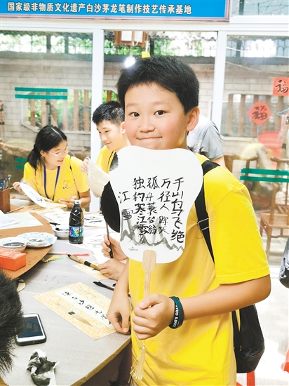美國華裔青少年李恩誠用茅龍筆在扇面上寫下唐詩。