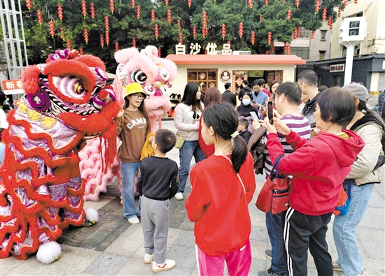 游客在長(zhǎng)堤歷史文化街區(qū)與醒獅合影。何雯意