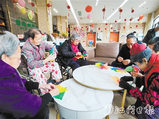 老人們圍坐在桌前，專(zhuān)注地制作小風(fēng)車(chē)。