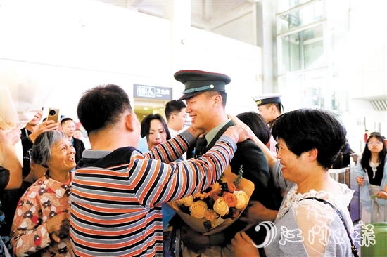 身著軍裝的返鄉(xiāng)退役士兵逐一出站，迎接他們的是鮮花與擁抱。
