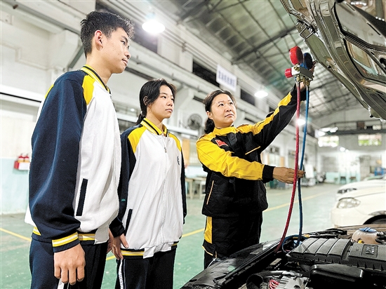 黃錚（右一）在汽修實(shí)訓(xùn)車間指導(dǎo)學(xué)生。