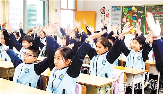 學生們在課桌前跟隨節(jié)奏做起“室內(nèi)課桌操”。