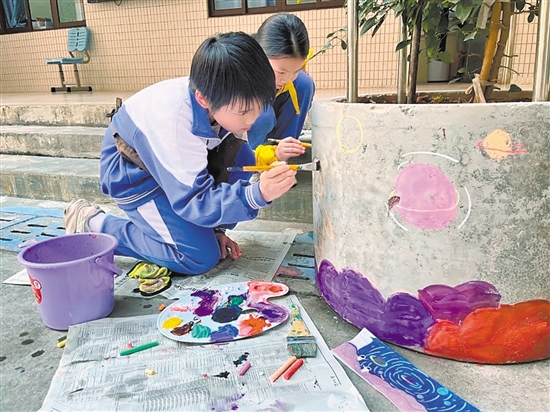學(xué)生們在校園內(nèi)的花墩上進(jìn)行精心繪制，為校園風(fēng)景增色添彩。