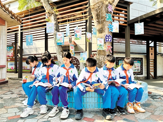 龍口鎮(zhèn)協(xié)華小學(xué)學(xué)生圍坐在“長滿書的大樹”下捧書共讀，成為該校一道亮麗的風景線。