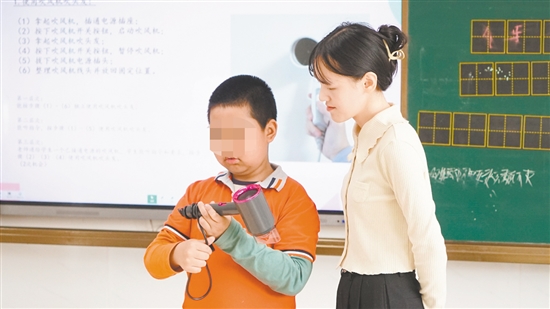 小明在老師指導(dǎo)下學(xué)習(xí)使用吹風(fēng)機(jī)。