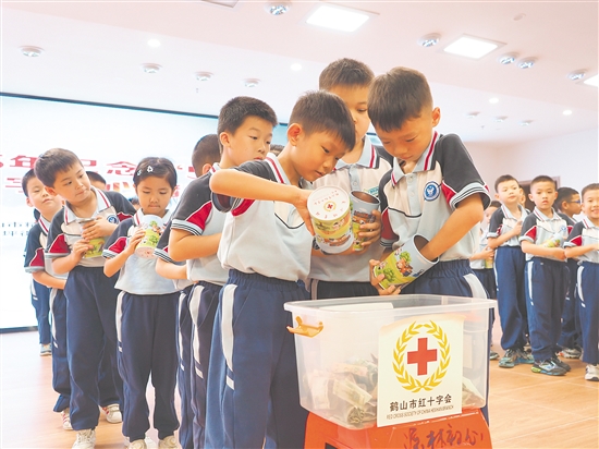 學(xué)生代表將愛(ài)心儲(chǔ)蓄罐里的零錢(qián)投入捐款箱，匯聚點(diǎn)滴愛(ài)心。