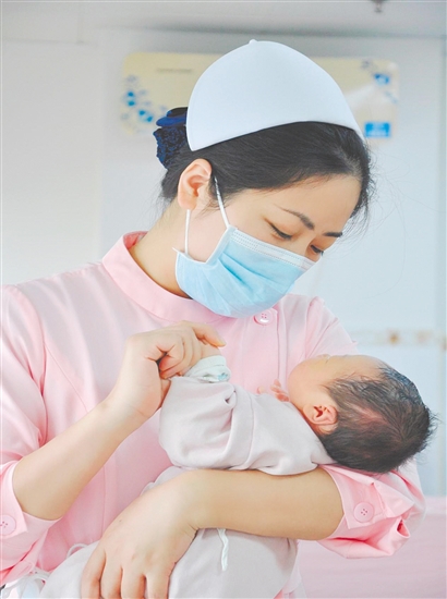 這是一雙托起生命的手。江門市中心醫(yī)院愛嬰?yún)^(qū)主管護(hù)師湯玲玲正在安撫哭鬧的寶寶。她一手環(huán)住襁褓，一手牽起寶寶的小手，動作舒緩而溫柔。在這里，生命的啼哭與溫柔的守護(hù)相遇，匯聚成世間至暖的力量。（林錦棠