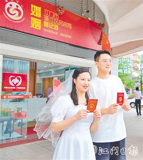 一對(duì)新人在蓬江區(qū)民政局婚姻登記處門(mén)口合影留念。