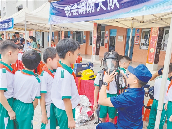 在消防救援大隊(duì)的展示區(qū)，同學(xué)們體驗(yàn)了消防員的空氣呼吸器等裝備。