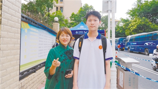 身著綠色旗袍的李女士與兒子合影。