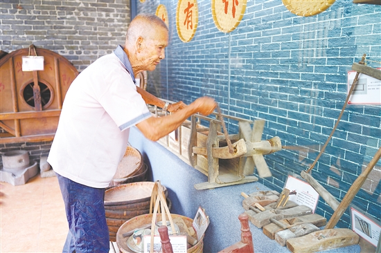 新華村打造農(nóng)耕文化展館，留住鄉(xiāng)村記憶。圖為村中老人向記者介紹農(nóng)具。