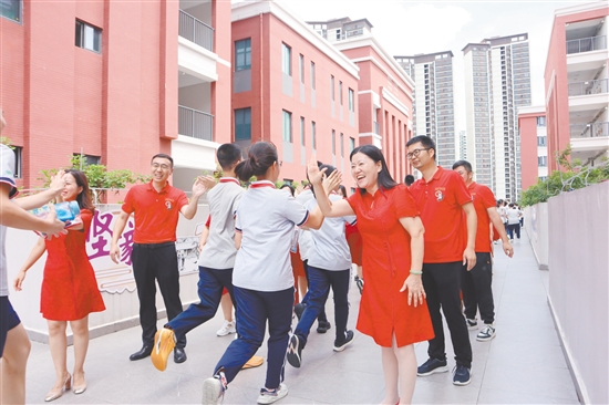 蓬江區(qū)紫茶中學(xué)的領(lǐng)導(dǎo)和老師們與考生們擊掌，為他們加油、鼓勁。