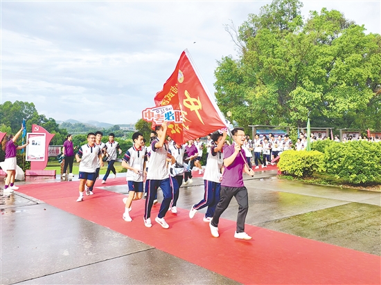 在臺山市武溪中學(xué)，老師揮舞著“中考加油”的紅旗為考生加油助威。