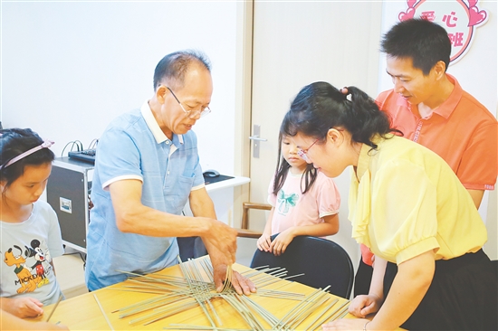 孩子和家長在手藝人的指導(dǎo)下學(xué)習(xí)編織小竹筐。