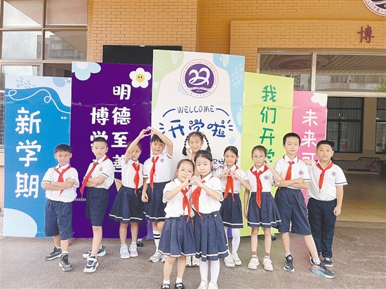 開學首日，農(nóng)林雙朗小學的學生們在學校精心準備的背景板前留影。