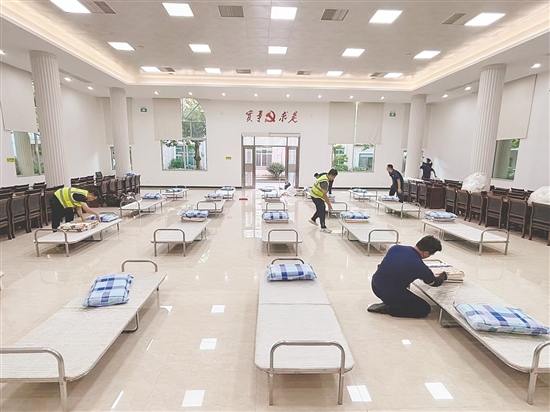 工作人員正在臨時庇護場所鋪設(shè)床位。