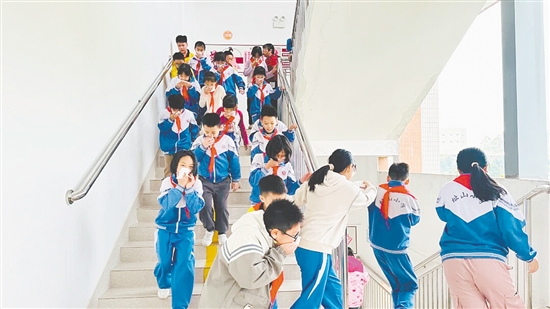 演練中，學(xué)生們彎腰低姿、用濕毛巾捂住口鼻，按照預(yù)設(shè)疏散路線(xiàn)快速向安全區(qū)域撤離。