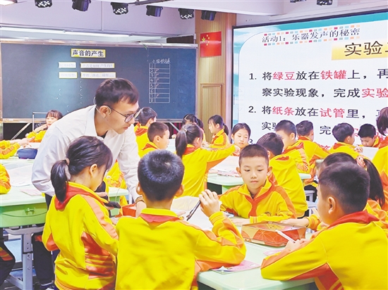 教師指導(dǎo)學(xué)生用橡皮筋、鐵罐、試管模擬樂(lè)器發(fā)聲。