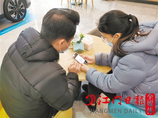 新能源汽車銷售人員協助車主用手機進行投保新能源汽車險。